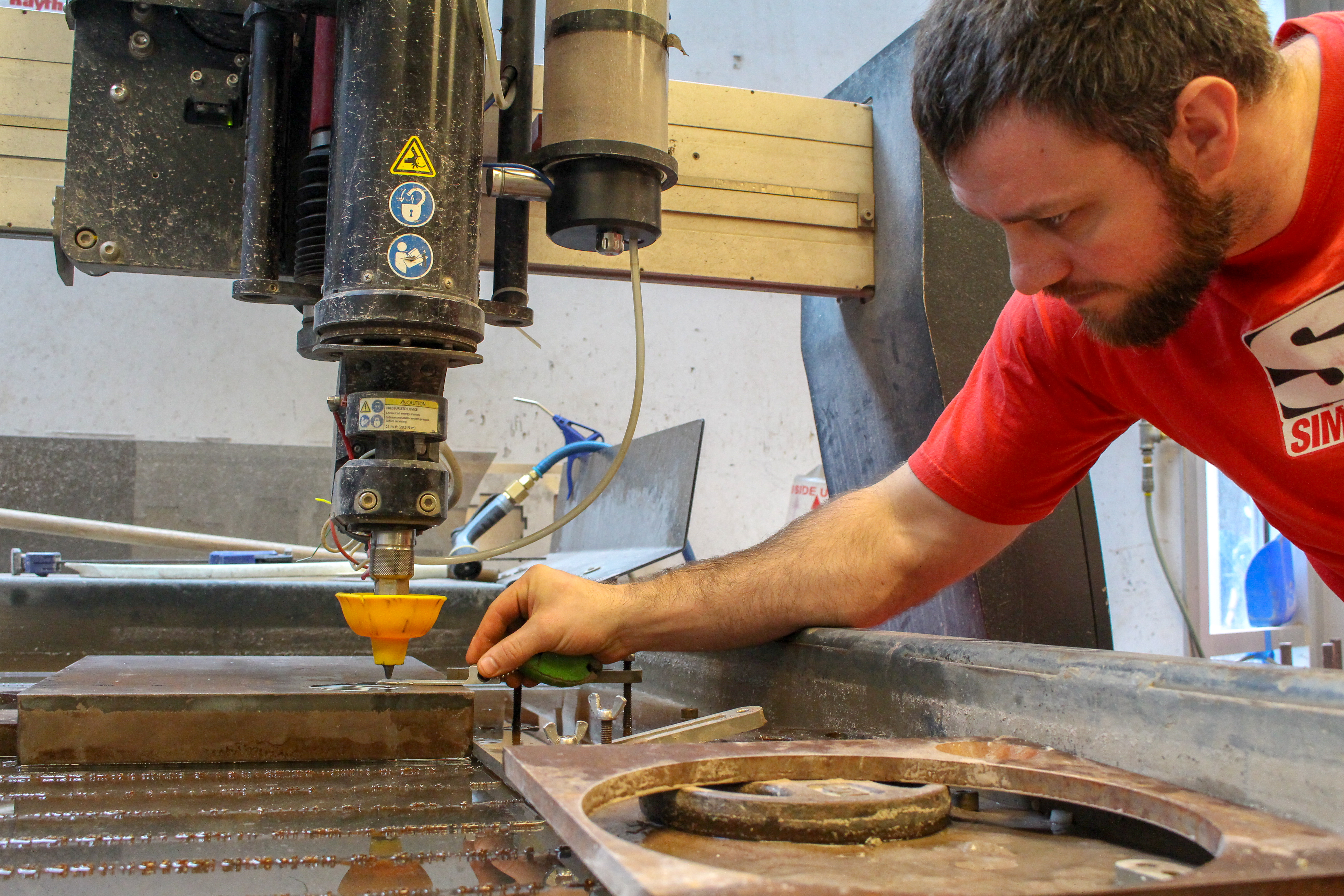 Man checking the height of a waterjet mixing tube relative to the cutting surface.